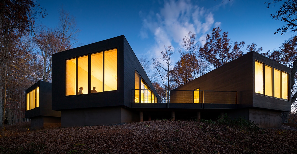 Each section of the home uses window walls to connect to the landscape and decks between buildings.