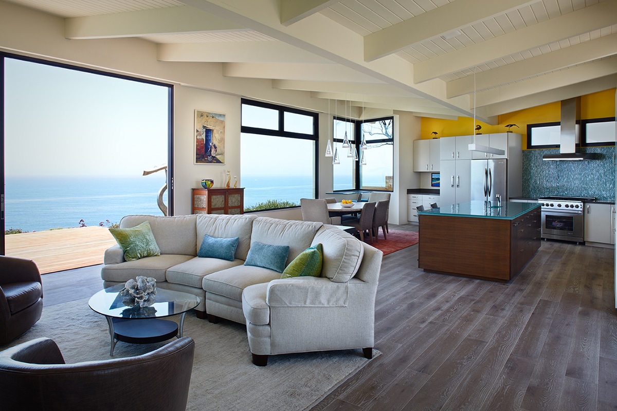 A large sliding glass door opens the living room to the ocean while large windows in the kitchen frame the view.