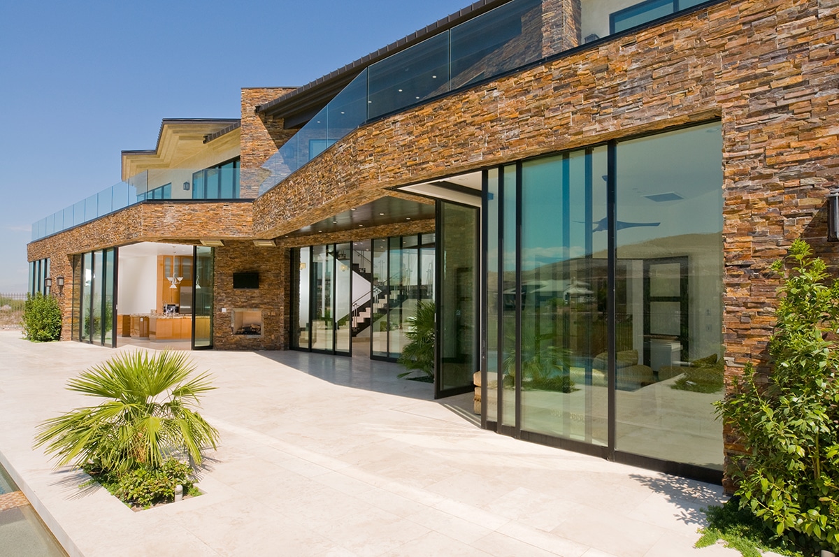 A front view of the two-story showroom with numerous multi-slide doors opening the home to the desert.
