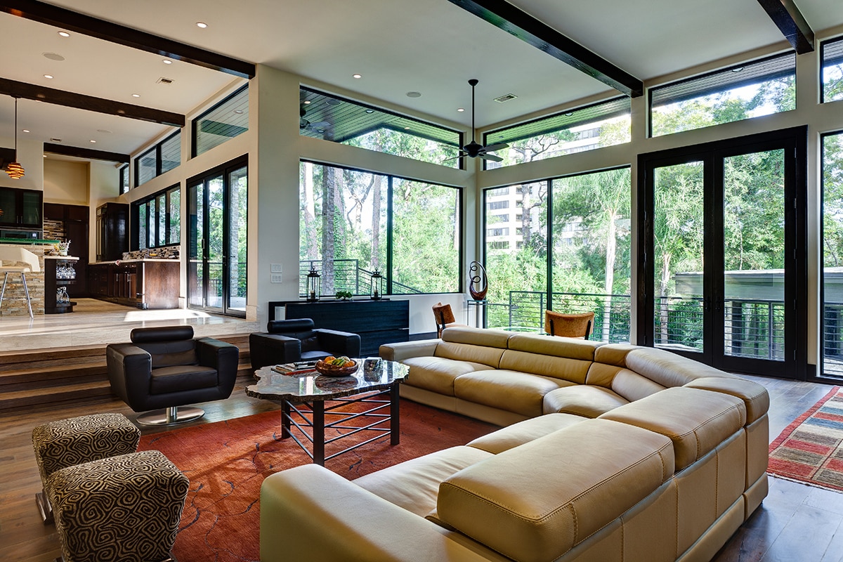 A rustic living room is surrounded by fixed windows and hinged doors, adding a modern touch and natural light.
