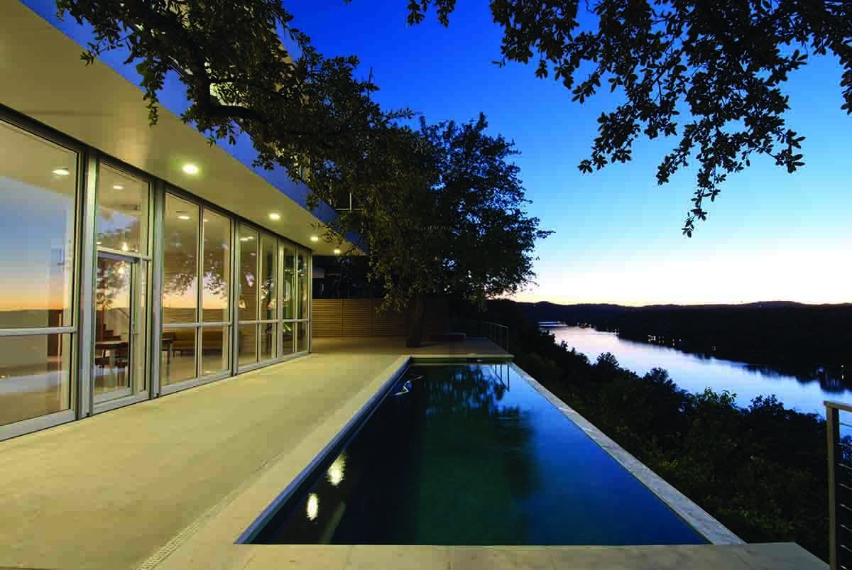 A view of the home’s complete glass wall that provides views of the pool and river outside.