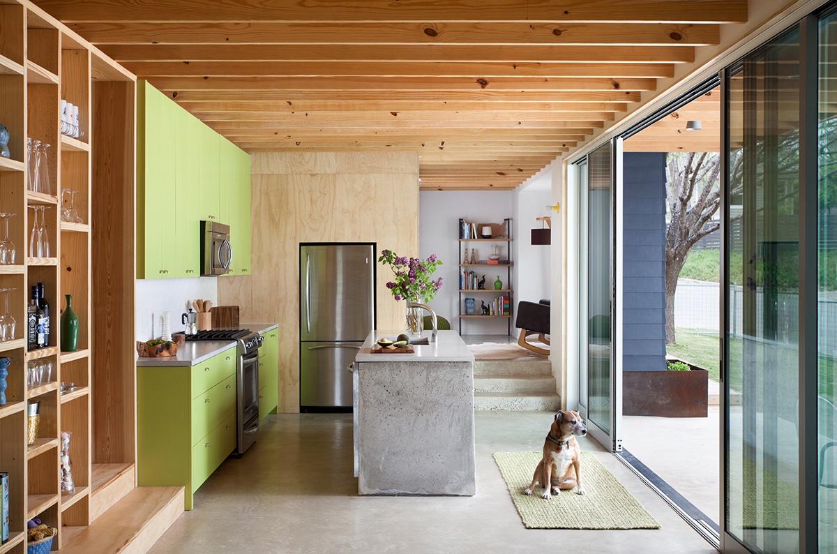 A large, open multi-slide door with a dog sitting in front of it connects the kitchen to the backyard.