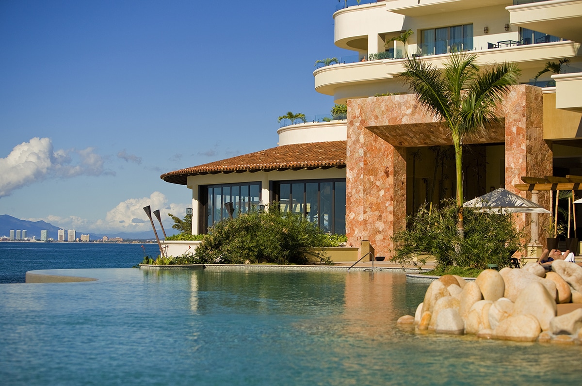 An outside view of the resort next to the ocean with large multi-slide glass doors.