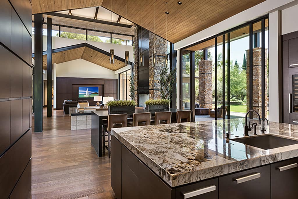 Floor-to-ceiling multi-slide doors and clerestory windows bathe the kitchen and dining area in light.