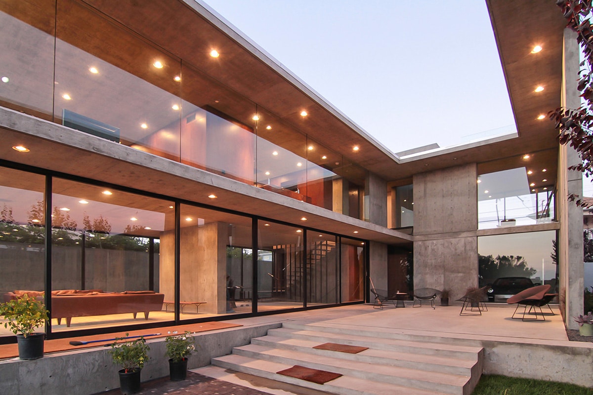 An astounding array of Western Window Systems multi-slide doors and window walls are exemplified on the two-story home by a minimal concrete divide.
