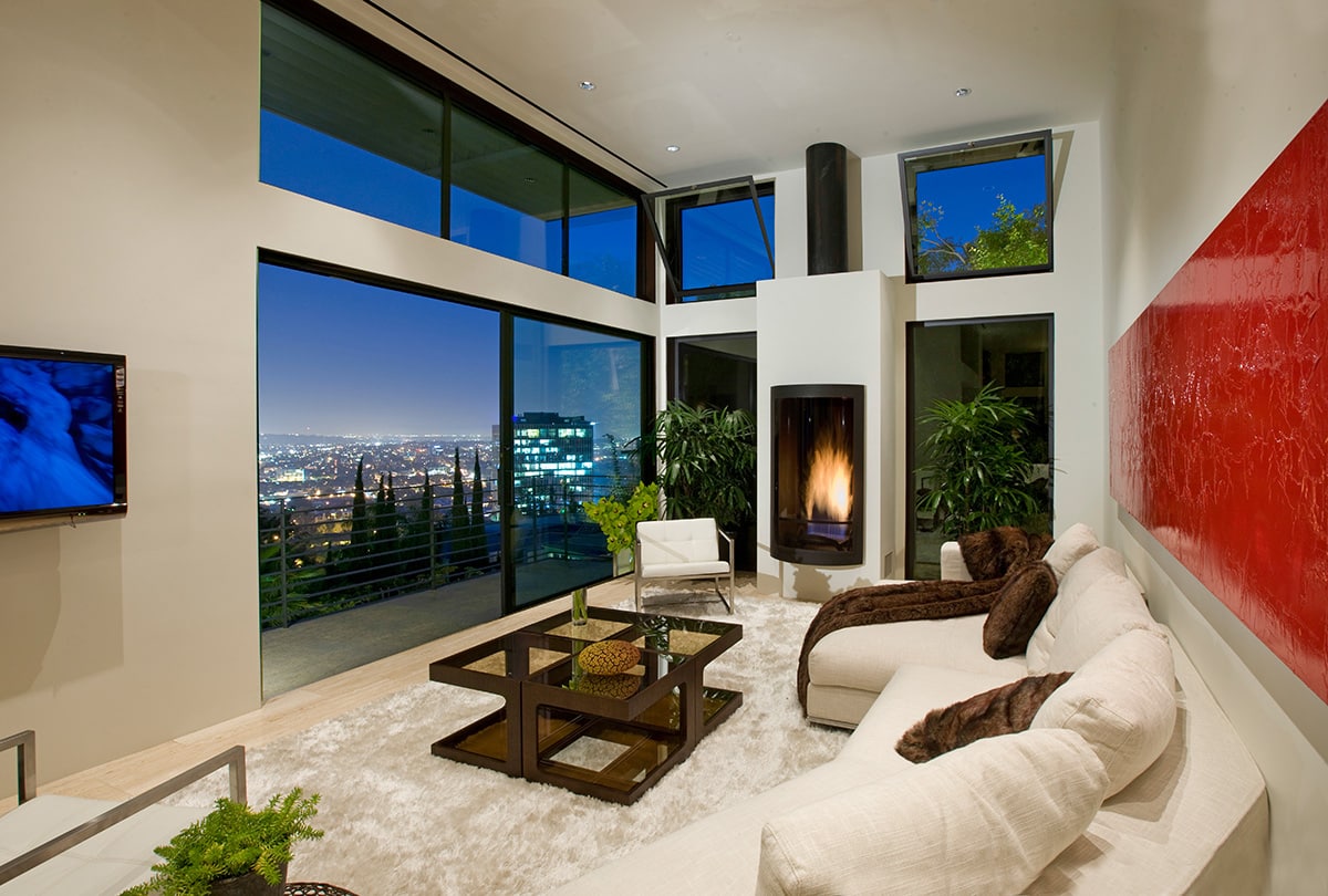 The living room with contemporary furnishing and a fireplace embraces contemporary-looking Western Window Systems doors and windows overlooking the city.