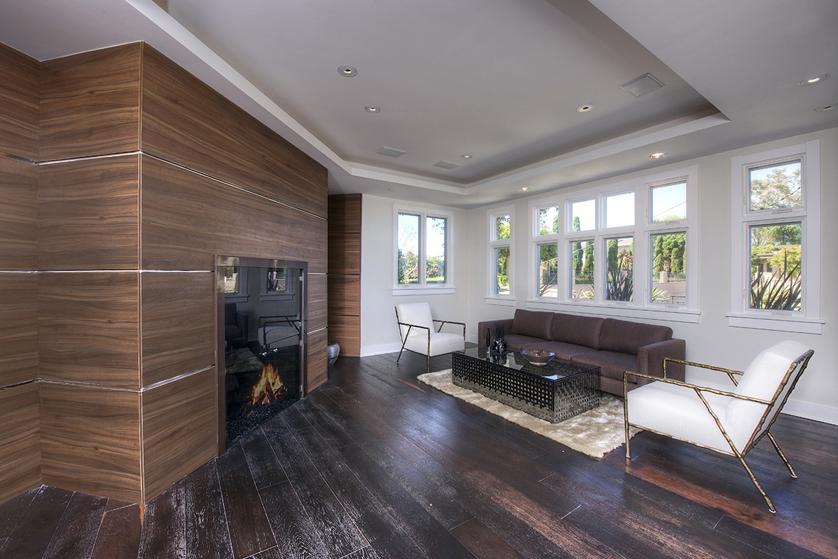 A bank of white Western Window Systems windows behind the couch and chairs lends itself nicely to the California style exhibited in this fireplace room.