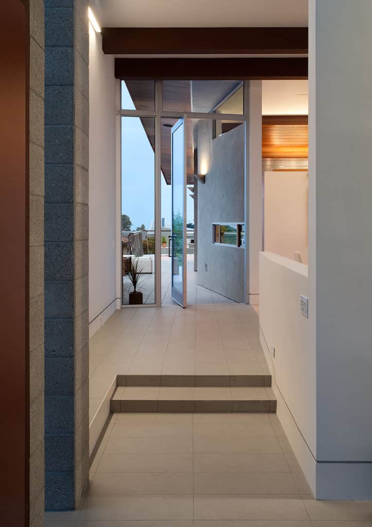 The balcony awaits those who walk through a modern-looking, half-opened pivot door.