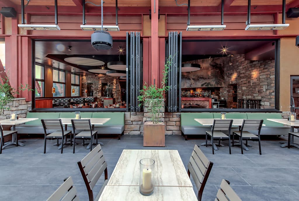 Fully open bi-fold windows connect the restaurant to the outdoor seating area.