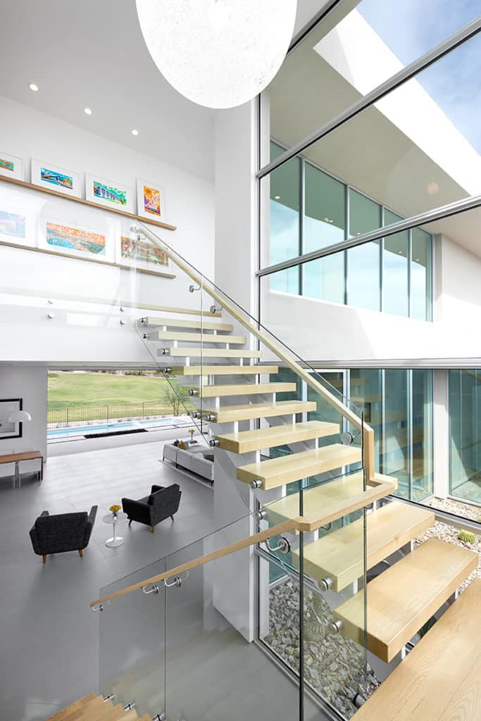 The home’s staircase is encased by windows leading up to the ceiling that complement the glass paneling stair rail.