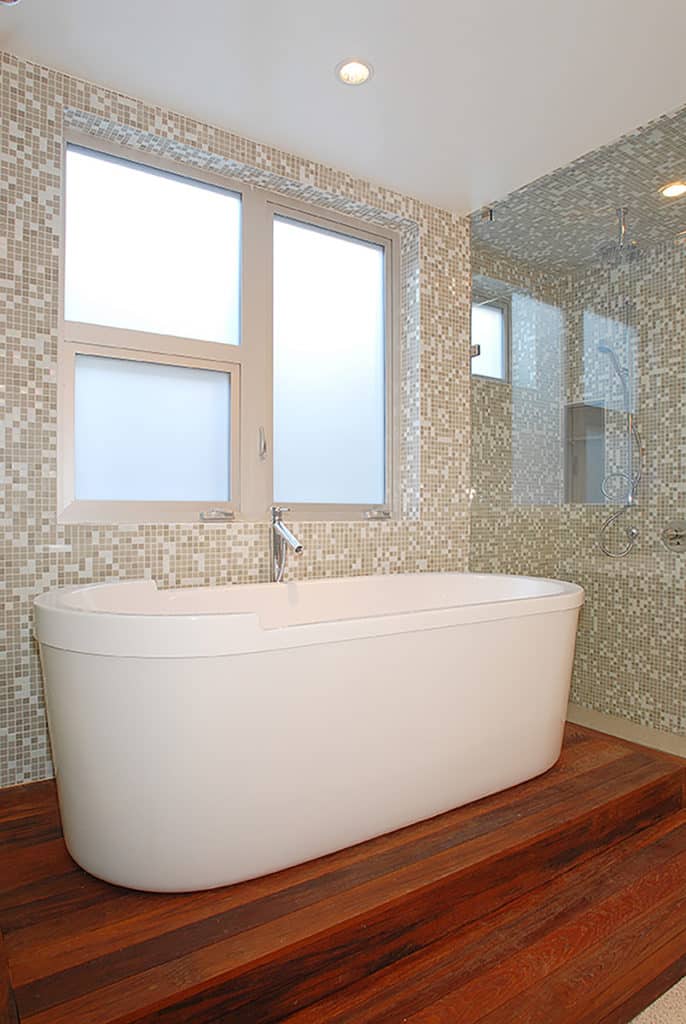 A bathroom showcasing frosted operating windows above the bathtub that let in fresh air when needed.