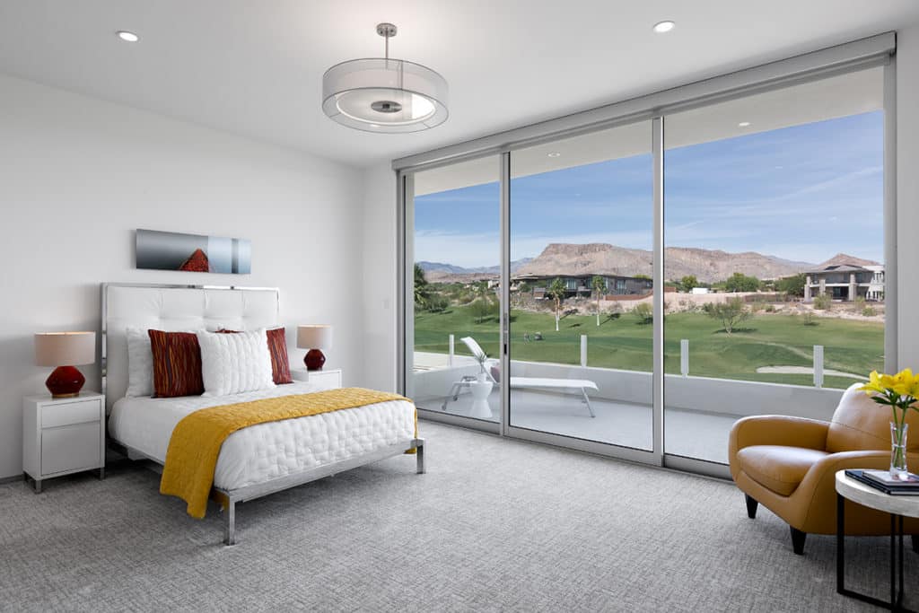The clean aesthetic of Western Window Systems’ products was perfect for the Shades of White design, like in this bedroom that connects to a furnished outdoor patio.