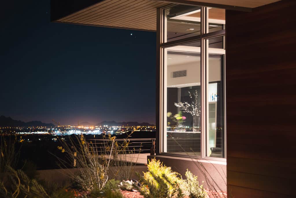 Views of the city at night are highlighted by the use of numerous fixed windows in the corner of this home.