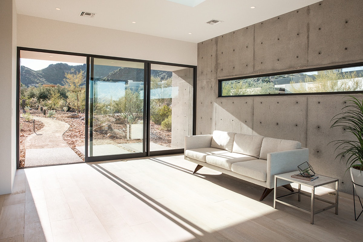 A large multi-slide door connects the indoors to the desert landscape with a path leading into the views.