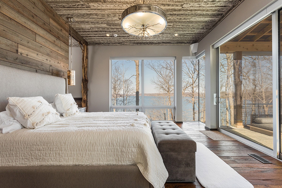 The master bedroom fills with natural light through a massive sliding glass door and a wall of windows.