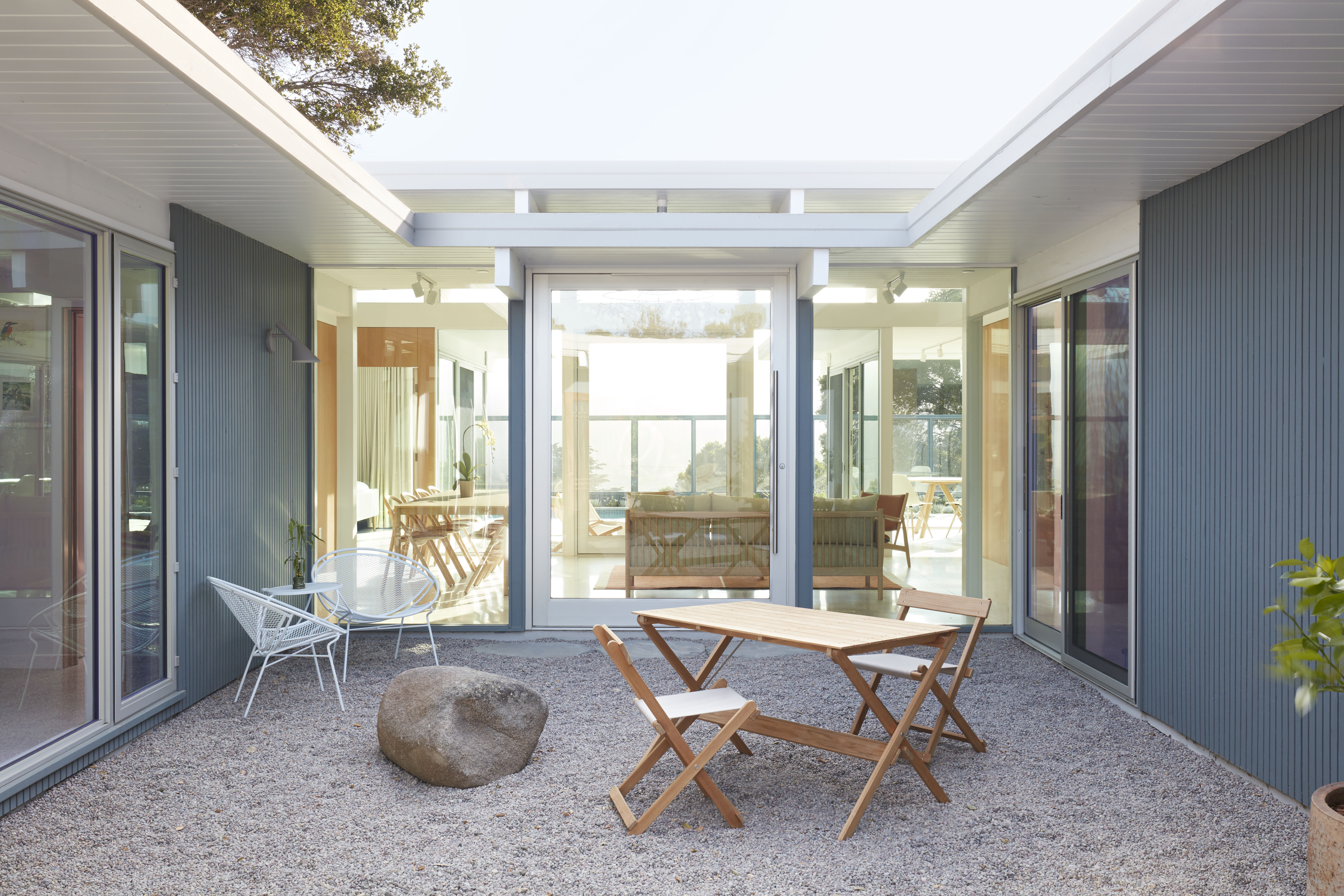 A pivot door surrounded by glass connects the indoor seating area to the outdoors.