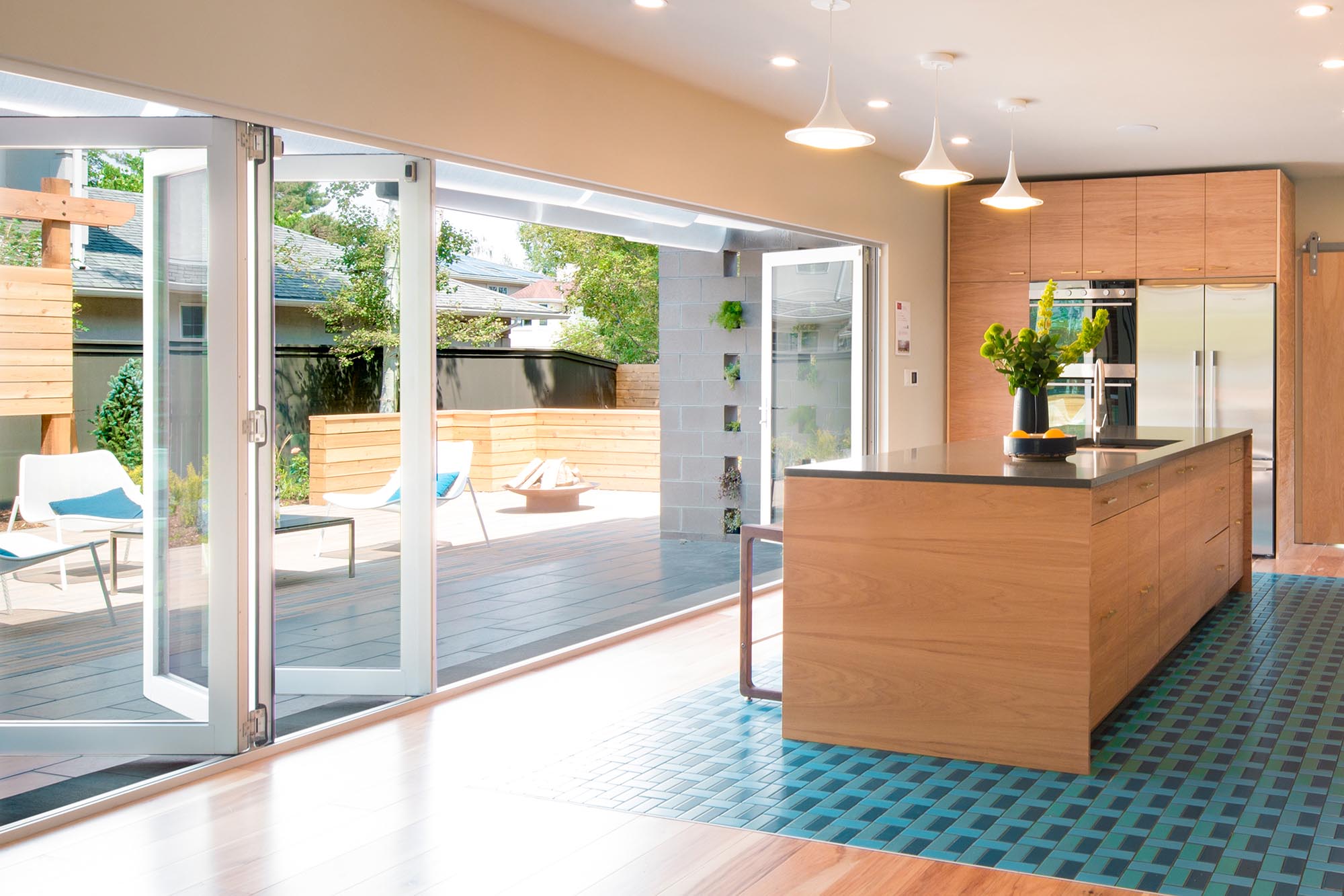 A wall length bi-fold door opens to connect the kitchen to the patio seating area.