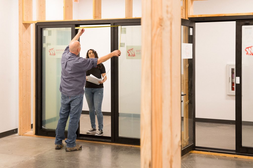An employee showing a customer the entrance width for a sliding glass door display.