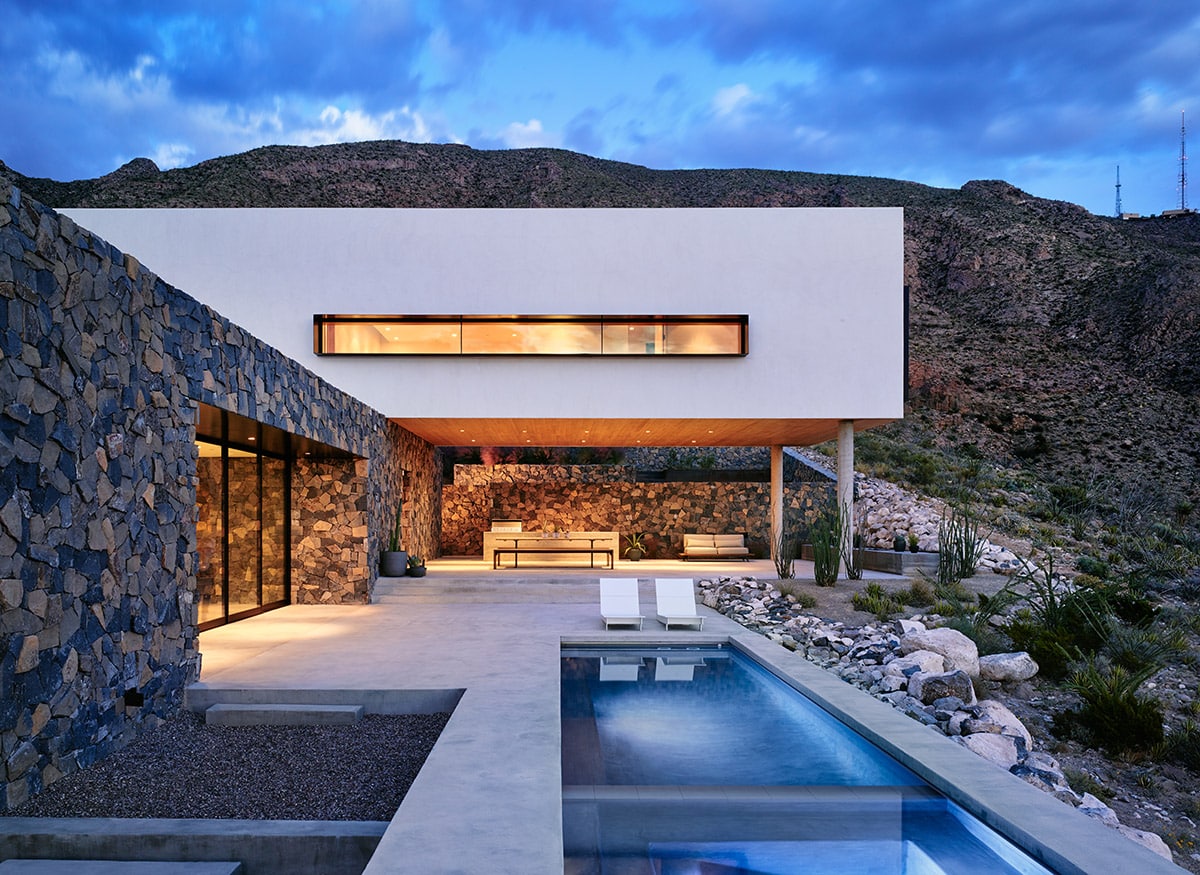 This Texas home uses volcanic rock basalt and granite on its façade to blend in with the mountainside and large panels of glass to frame mountain views.