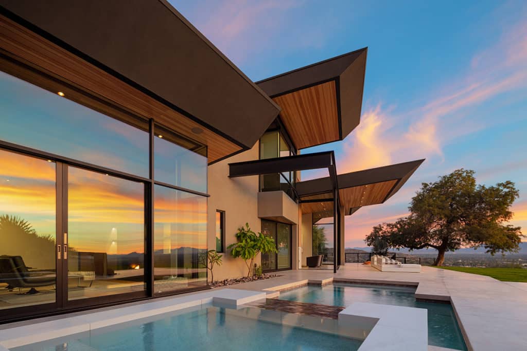The exterior of a home with a massive glass wall with bi-parting, sliding doors.