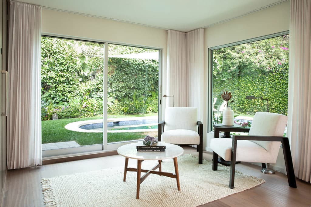 The lounge area opens to the green backyard through a large sliding glass door.