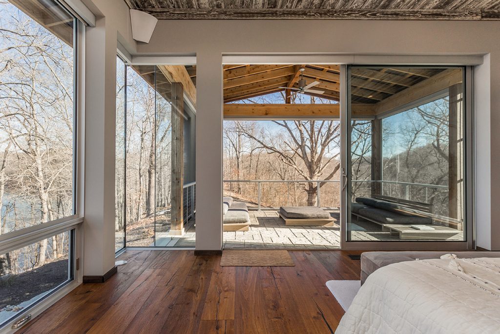 A huge sliding glass door opens from the master bedroom to an enclosed outdoor living space.