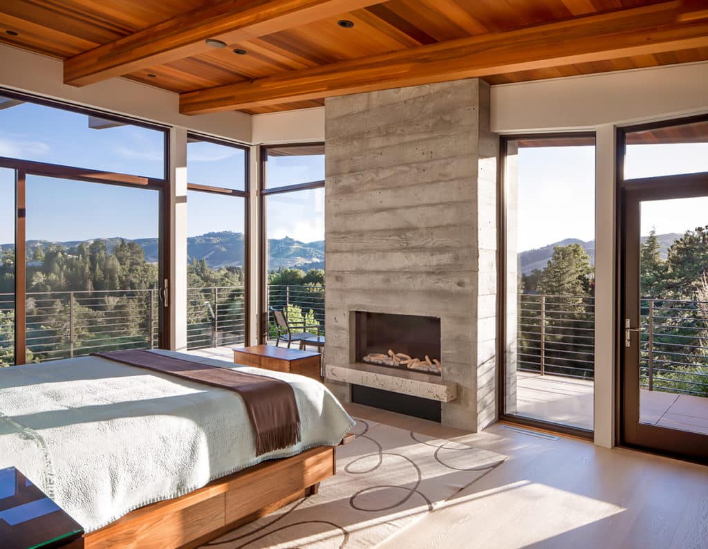 This master bedroom has nearly all glass walls that provide forest views.