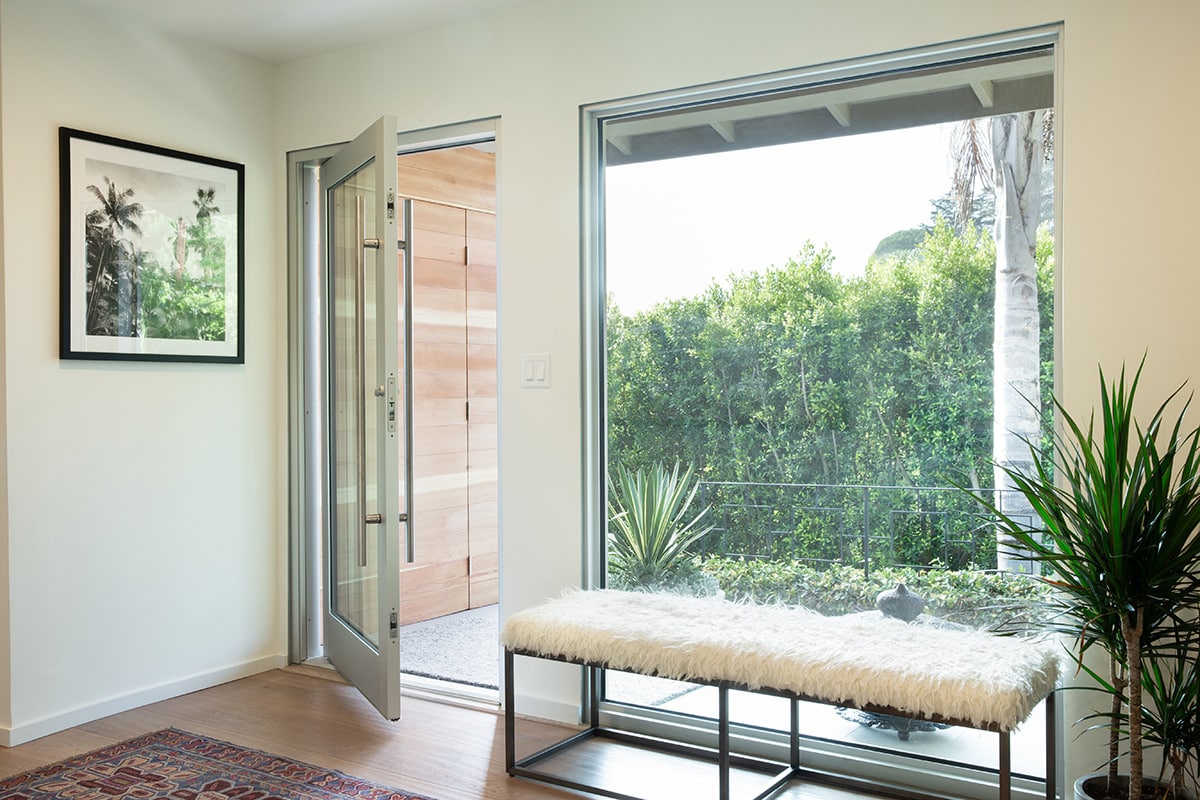 A pivot door and large fixed window in the home’s entryway provide energy efficiency to go along with clean, contemporary aesthetics.
