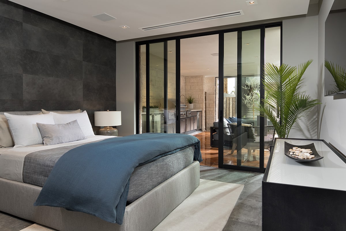 A 4-panel multi-slide door connects a modern bedroom to the outdoor seating area.