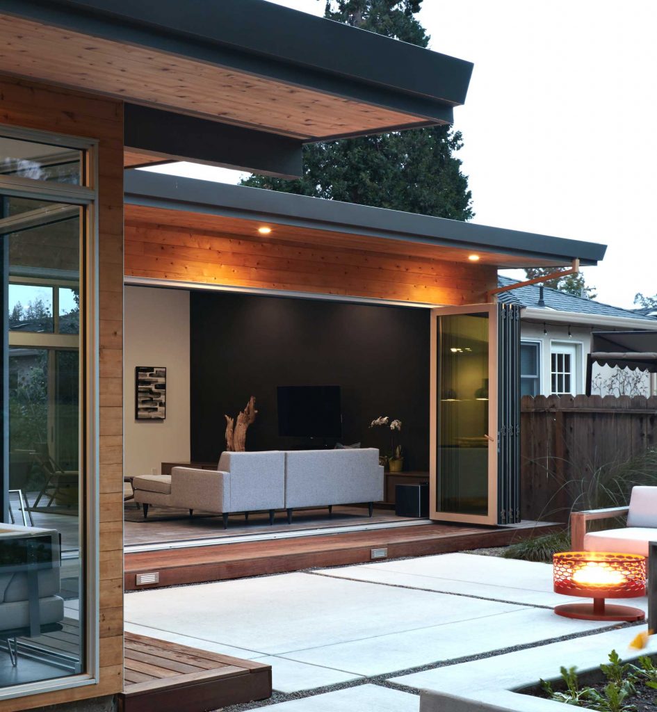 An open bi-fold door connects the living room to the patio.
