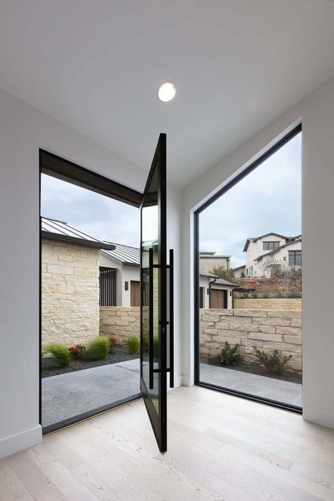 A glass pivot door sits at a 90-degree angle from a fixed window the same size.