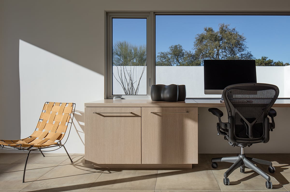 A fixed and operable window bathes this home office in natural light from behind the computer.