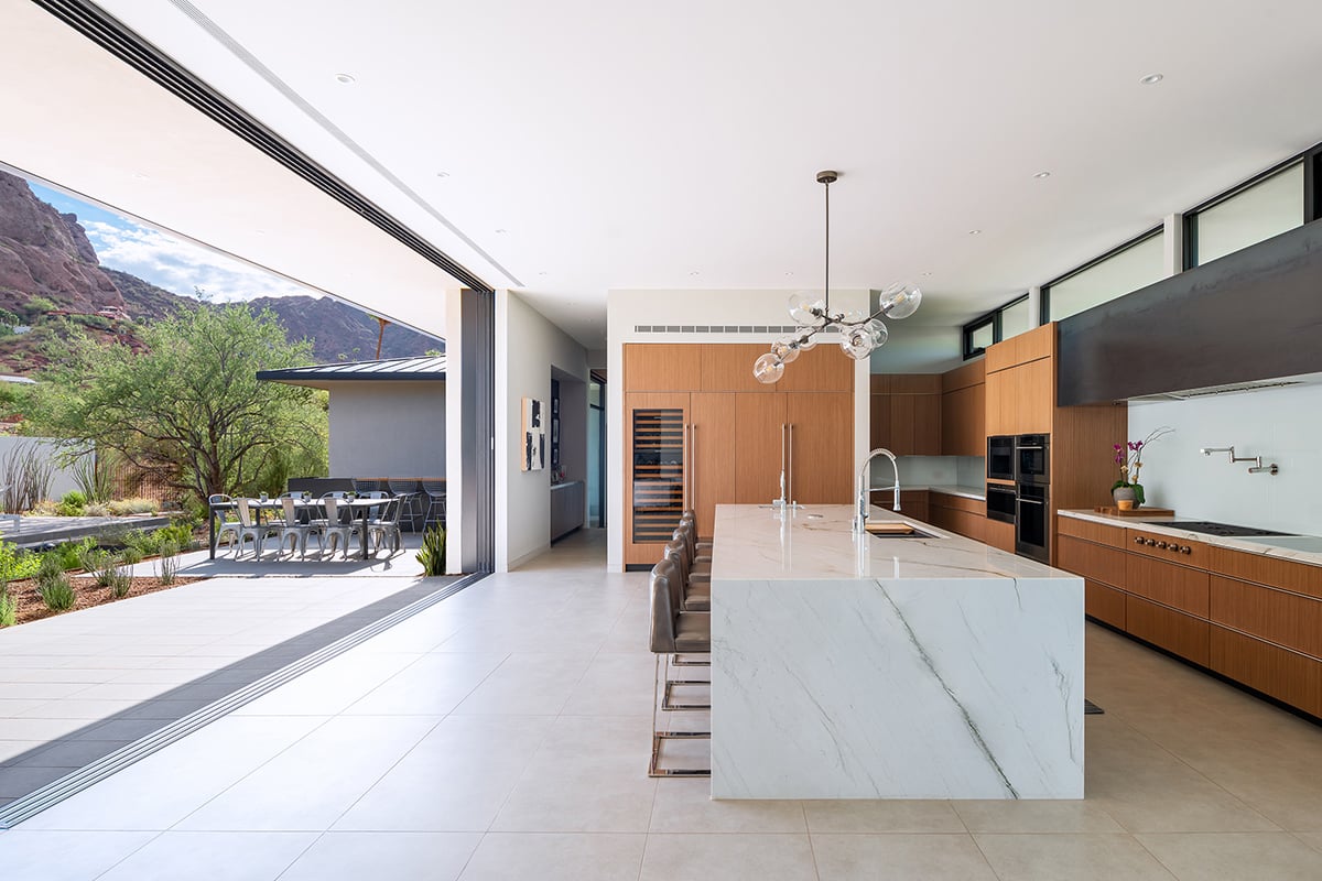 A moving wall of glass opens the kitchen of the home to an outdoor space at the base of Camelback Mountain.