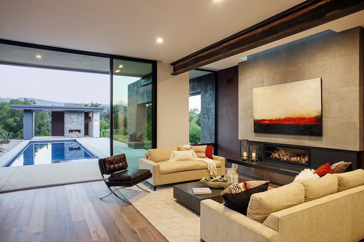 A view of a living room connected to the backyard with a pool through a wall-to-ceiling multi-slide door.