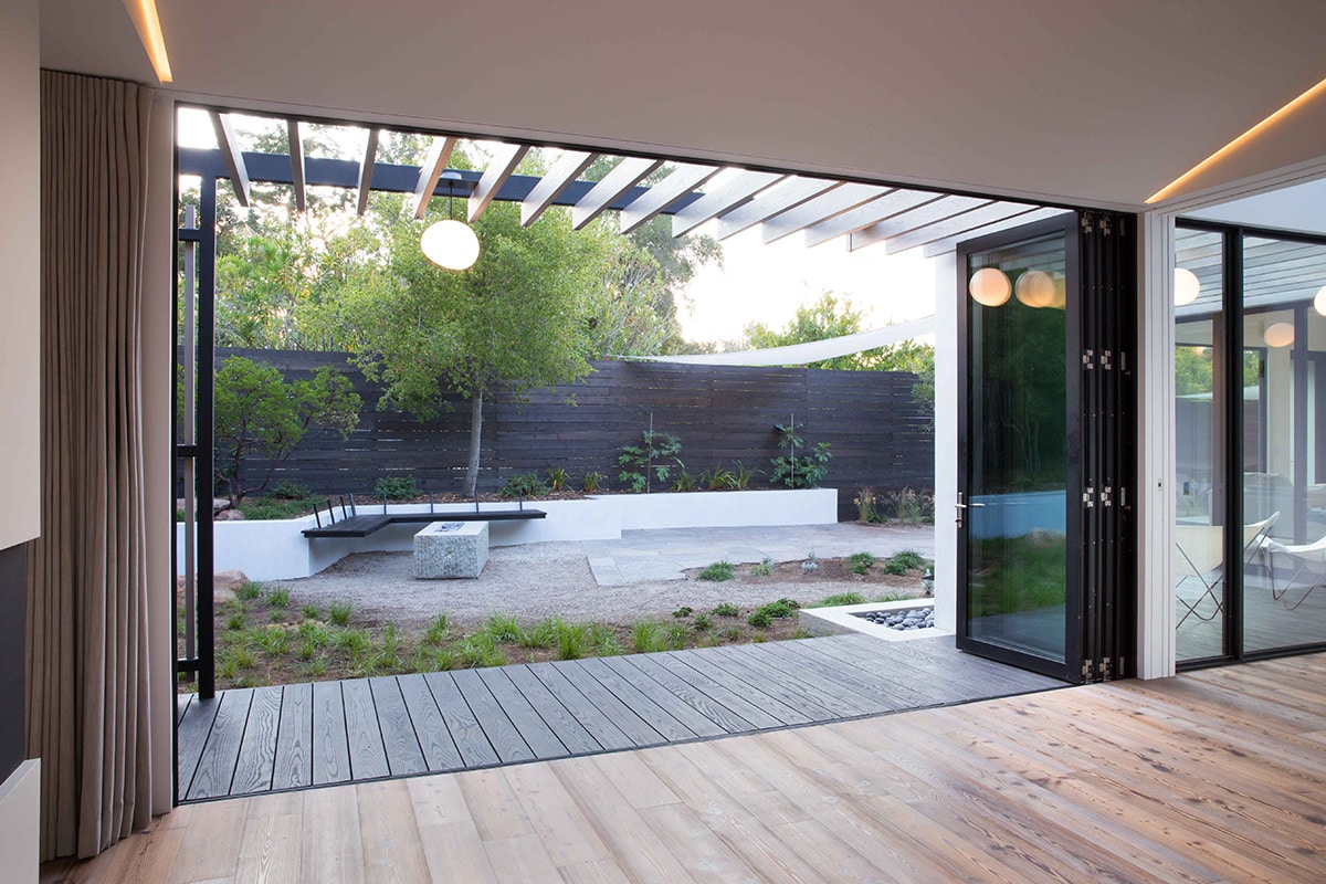 This giant bi-fold door opens to a covered boardwalk-style walkway and the backyard.
