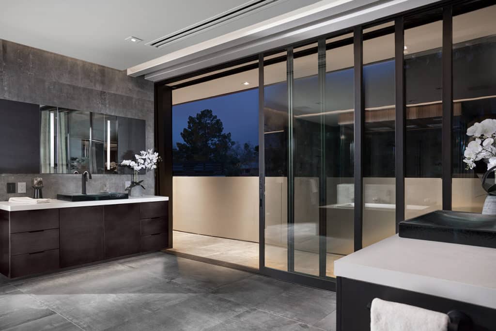 A multi-slide door wall of glass completely opens the master bathroom to the balcony and views outside.