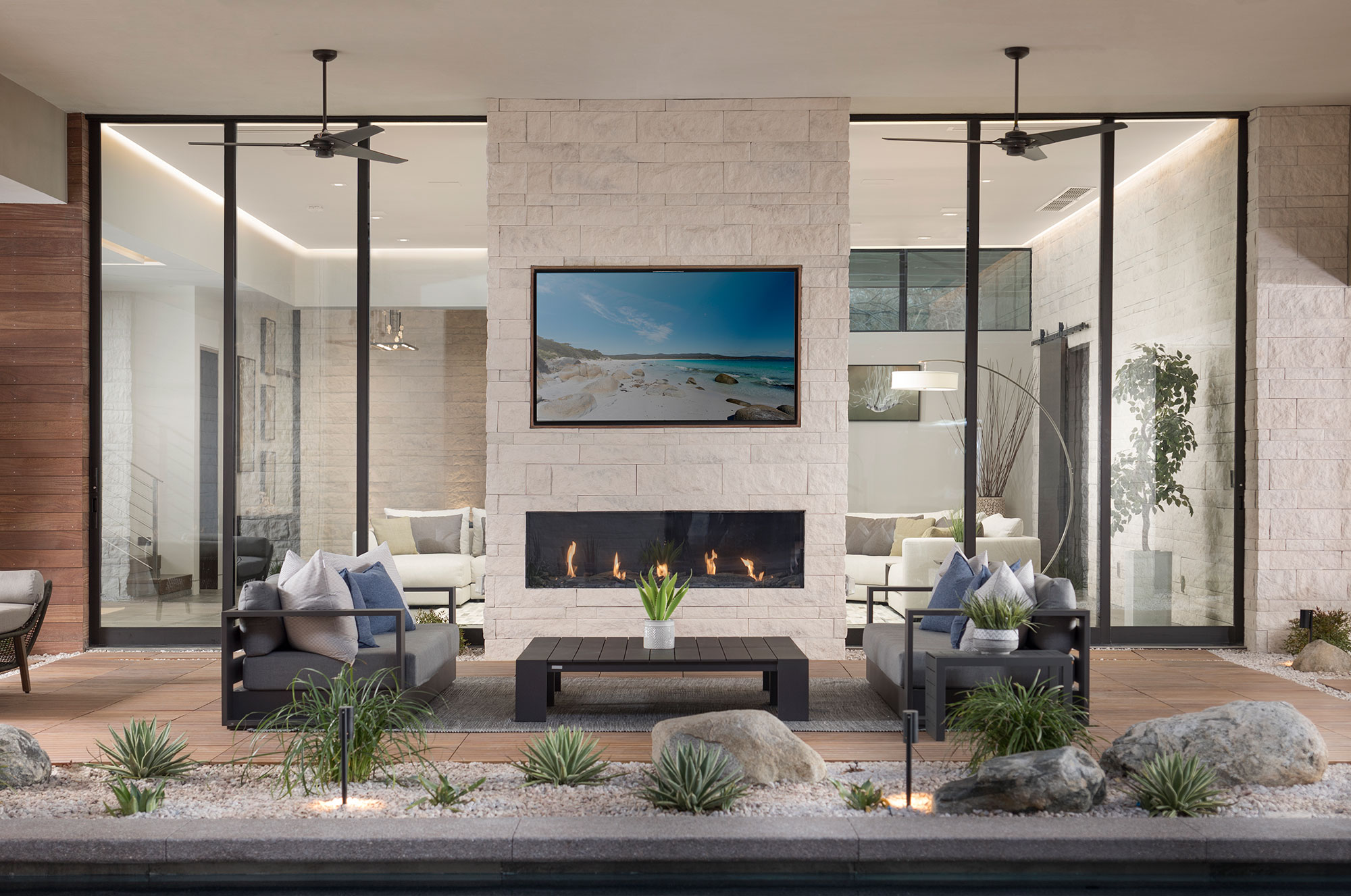 Two massive, floor-to-ceiling multi-slide doors surround an outdoor fireplace.