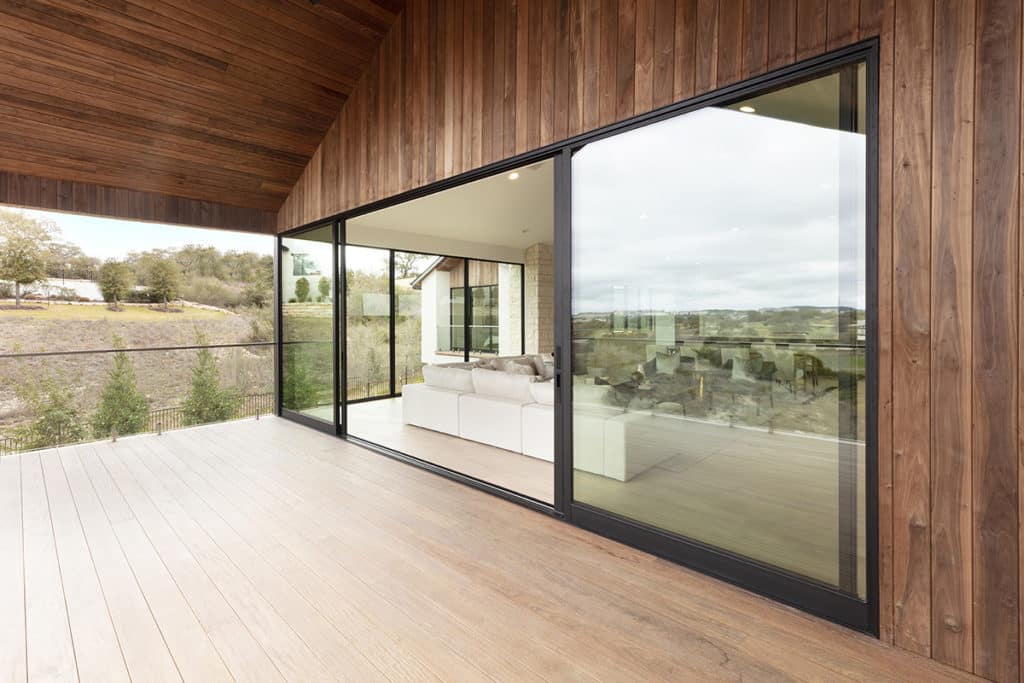 Floor-to-ceiling glass walls open onto a covered terrace with high-pitched wood ceilings and a long view of the sprawling, sagebrush-dotted landscape.