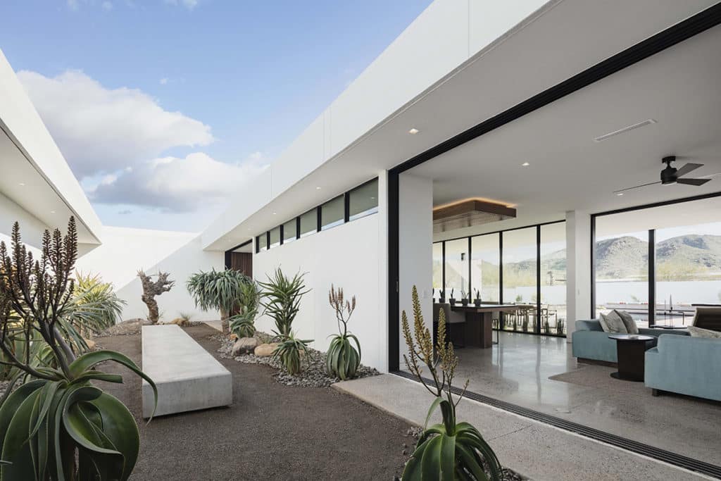 The living room extends to a desert oasis courtyard through a large, pocketing multi-slide door.