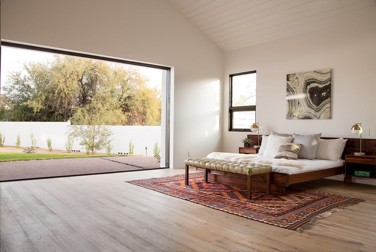 A seamless merging between the indoors and outdoors is made possible in this bedroom through a large, pocketing multi-slide door.