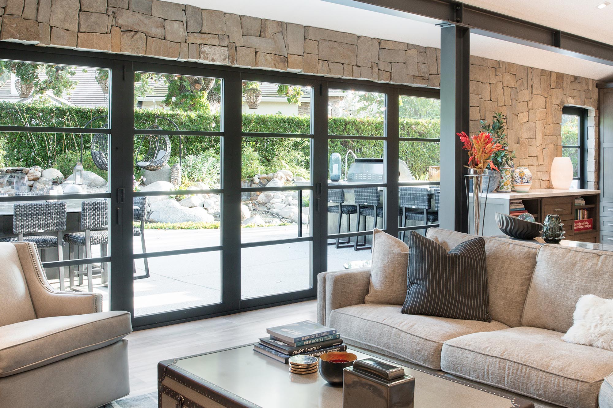 The wall length bi-fold door with divided lights frames backyard views in this living room.