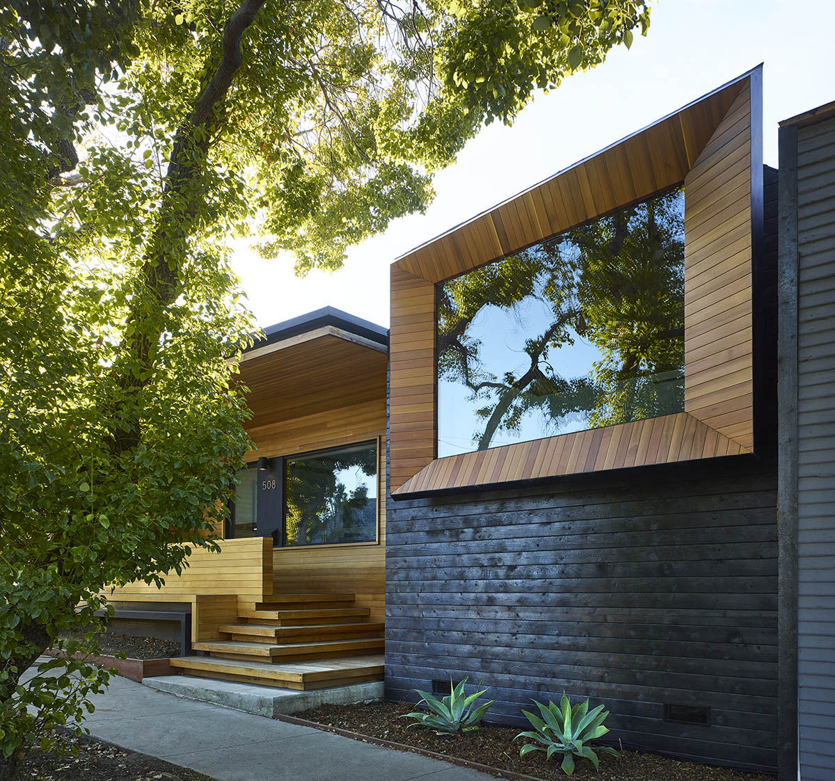 A customized and oversized window that sits in a wooden frame gives the front of the house a unique entrance.