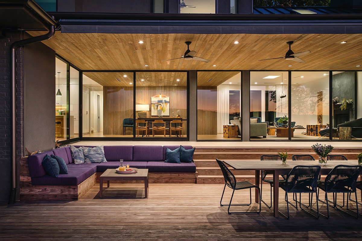 A window wall connected to an open-corner configuration of multi-slide doors creates a moving façade of glass that opens to the backyard deck.