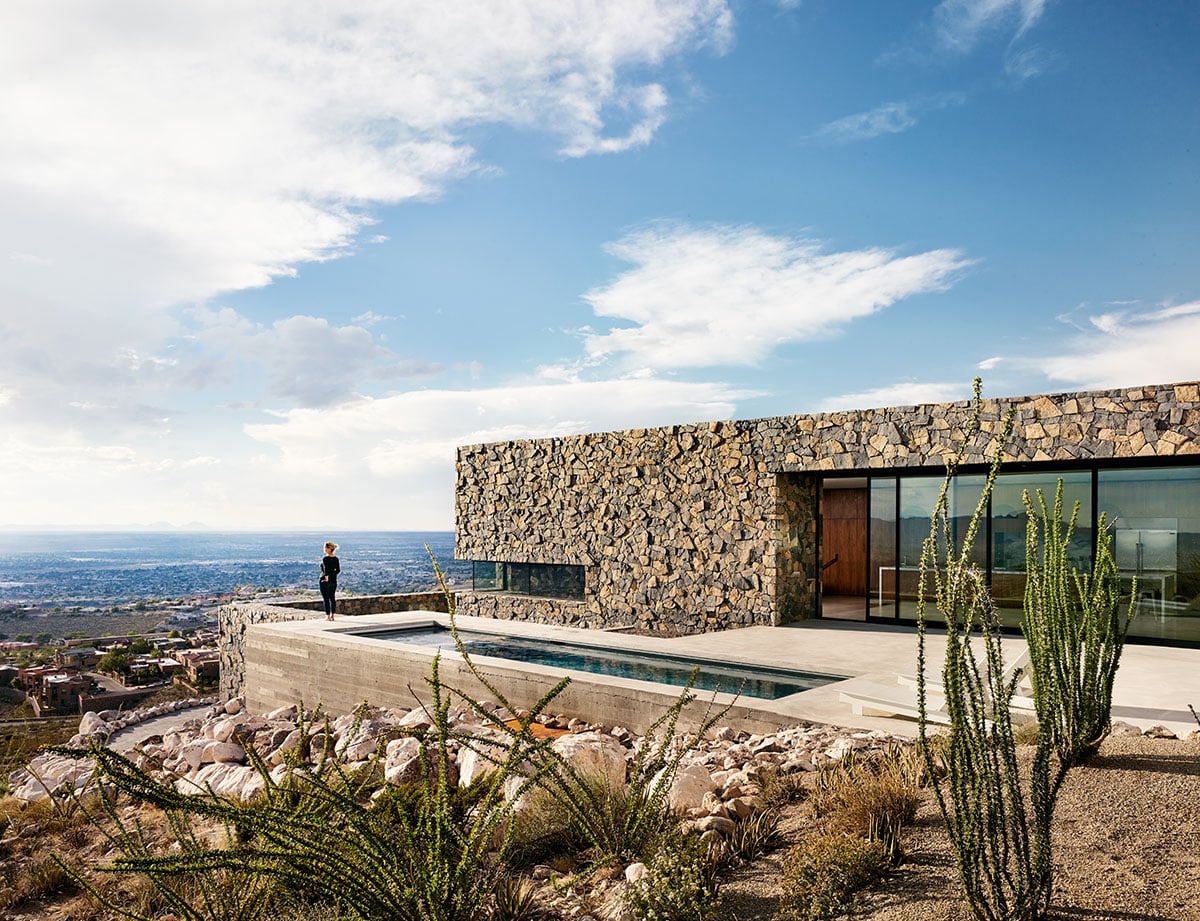 A view of a home that blends into its surroundings using natural elements with a massive multi-slide door.