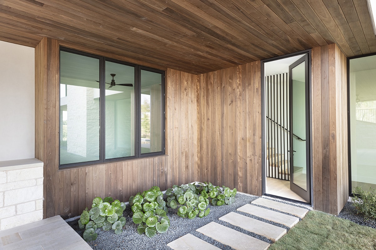 A large, hinged door gives a view of the outside entry way of mixed desert landscaping and grass.