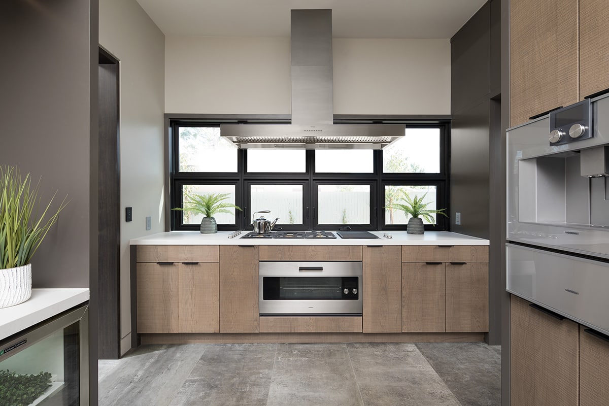 A backsplash of black-bordered fixed windows and multi-slide windows complement the kitchen interior.