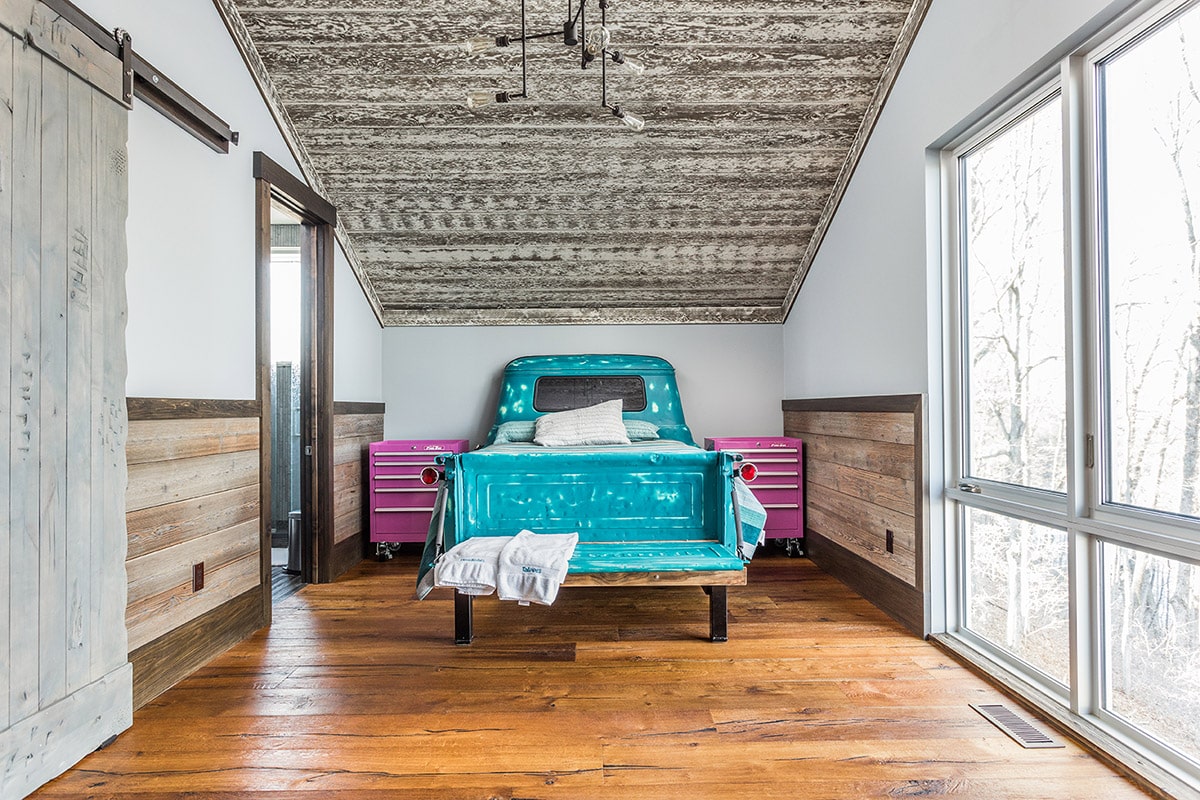 Huge panels of glass augment the sense of fun in the Lake Monroe mansion, like in this bedroom with a blue, truck-shaped bed.