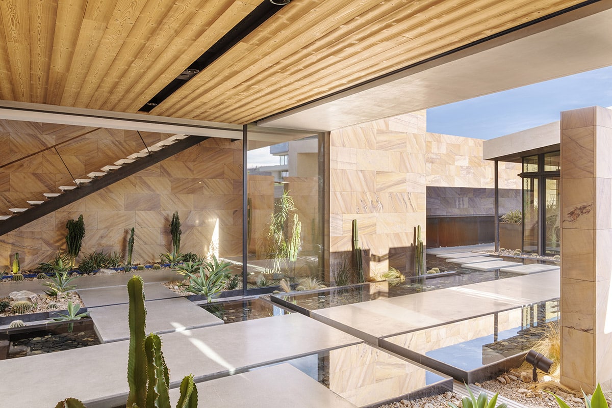 A view of the foyer with open multi-slide doors that connects the room to the desert landscaping and pools around the entrance.