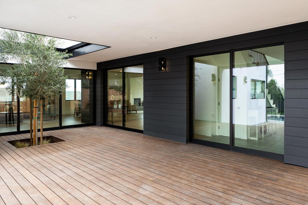 Two massive sliding glad doors connect the home to an enclosed wooden patio.