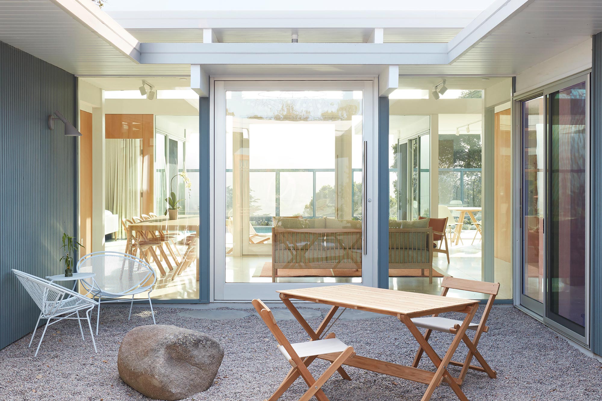 A massive, hinged door surrounded by fixed windows connects an outdoor seating are to the indoor seating area.